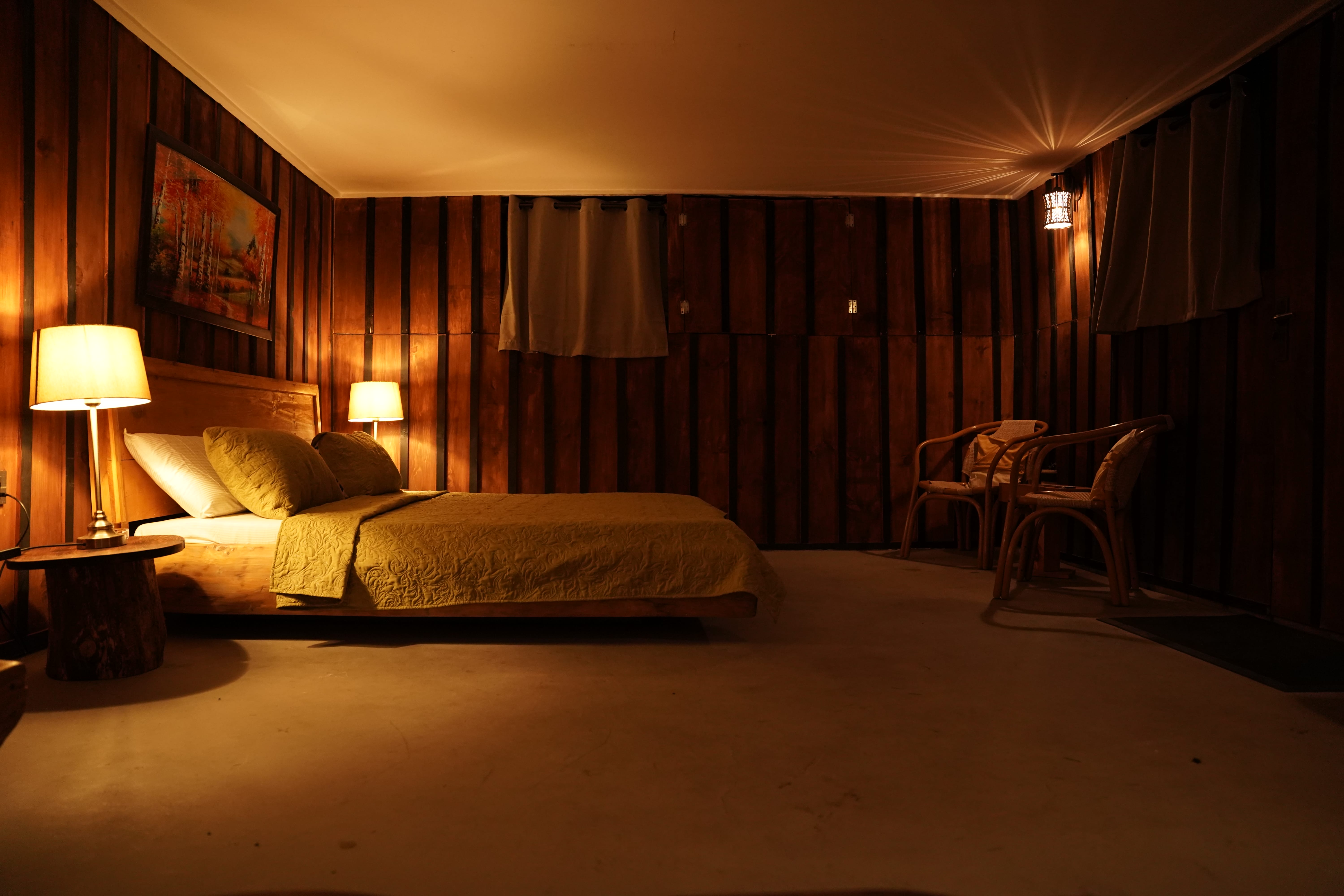 Spacious bedroom with rattan chairs and ambient lighting