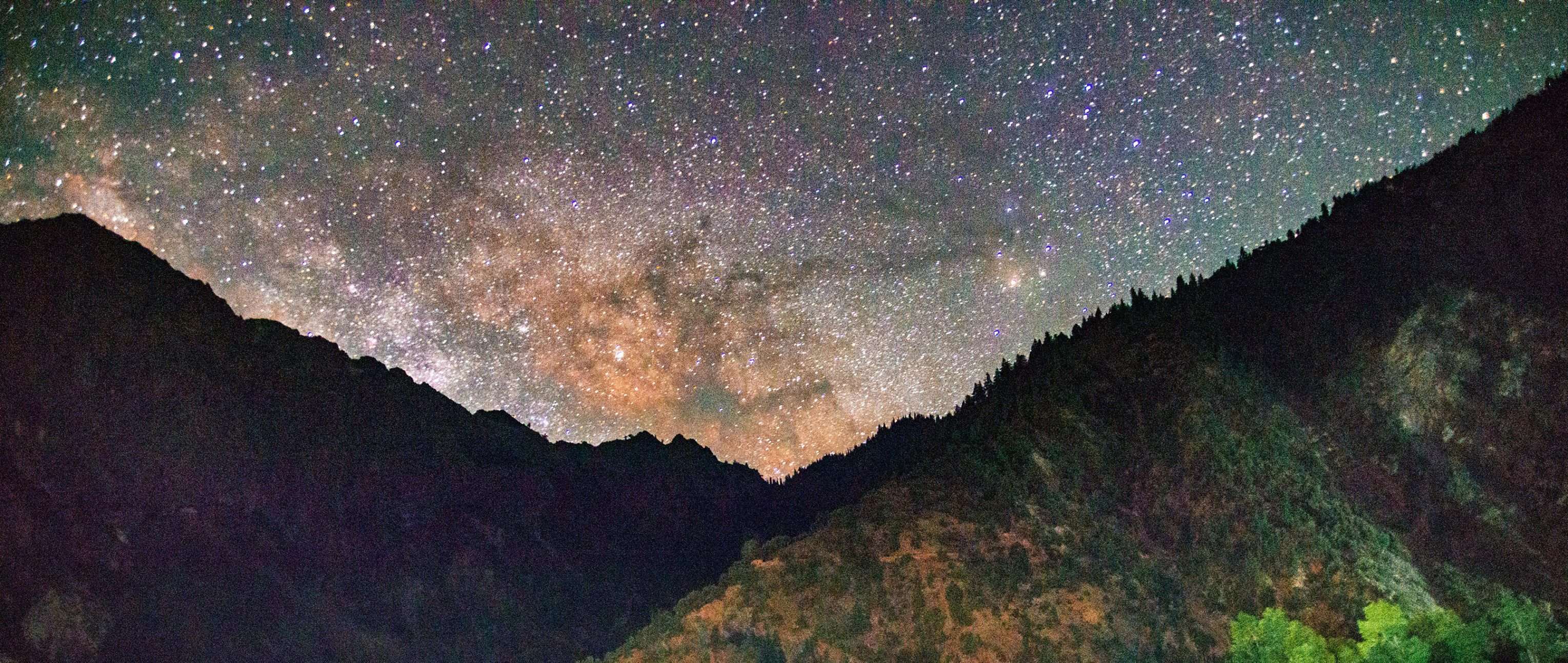 Milky Way stretching across the night sky over Hindu Kush mountains and forest